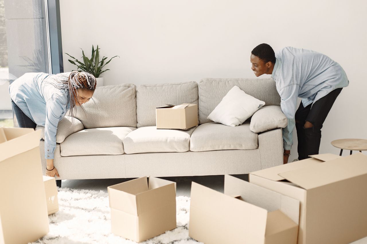 team-01 Happy couple setting up a sofa in their new home surrounded by moving boxes.